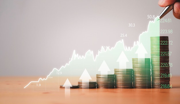 Investor hand writing stock market increasing graph chart with coins stacking for trader investment analysis concept