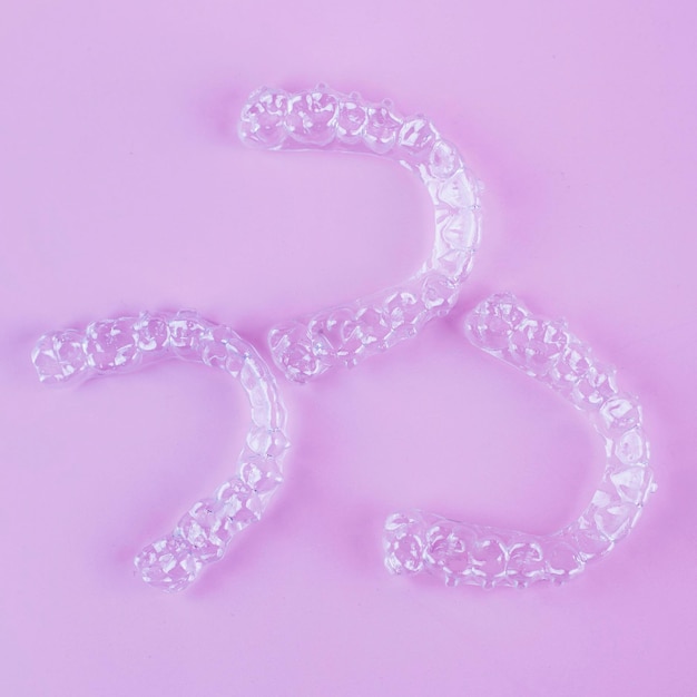 Invisible dental teeth brackets tooth aligners on pink background Plastic braces