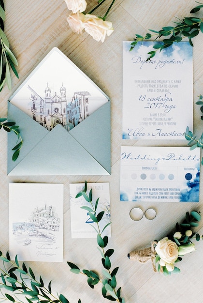 Invitation cards with envelopes for the wedding lie next to the wedding rings