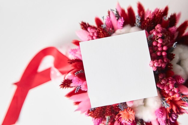 Modello di invito o biglietto di auguri e bouquet di fiori secchi sul tavolo bianco