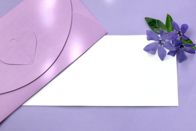 招待状のモックアップ空の空白のグリーティングカードとツルニチニチソウの花の封筒