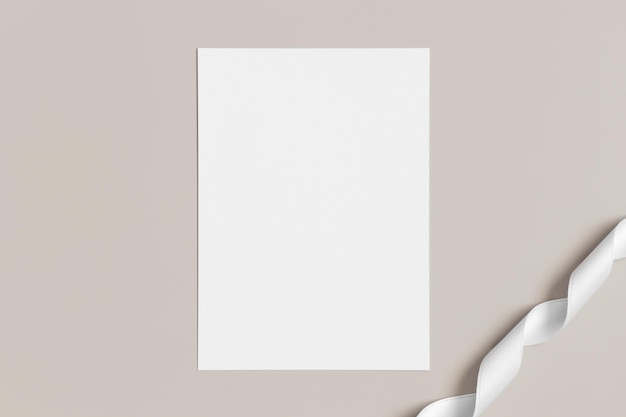 Invitation white card mockup with a satin tape on a beige background 5x7 ratio similar to A6 A5