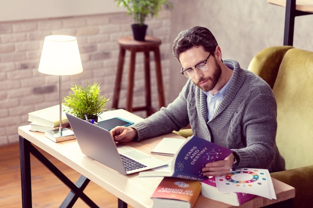 Invloed van sterren aangename man met een baard die boeken bestudeert terwijl hij als astroloog werkte