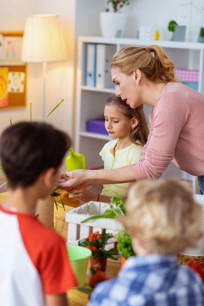 Involving pupils. Young excited blonde-haired teacher involving pupils into ecological campaign