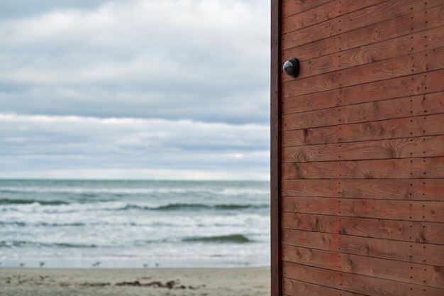 IP CCTV camera with home security system installed on wooden wall against backdrop of seascape. Protected area, coast guard station.