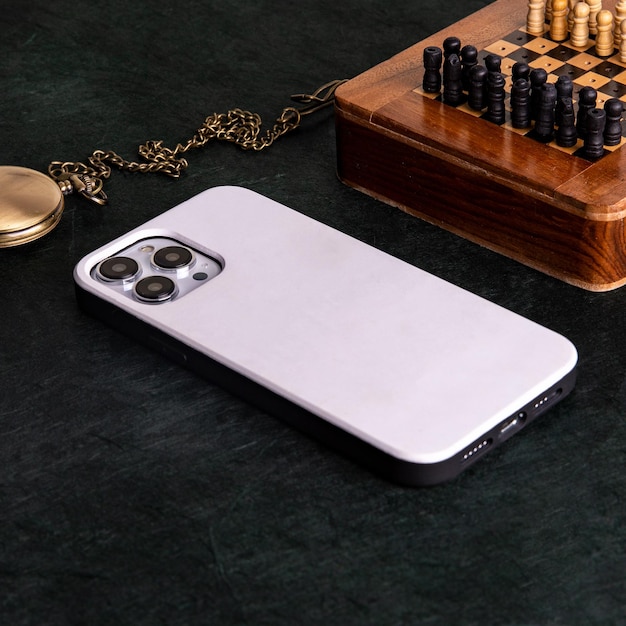 An iphone with the back of the case on the back is on a table next to a chess board.