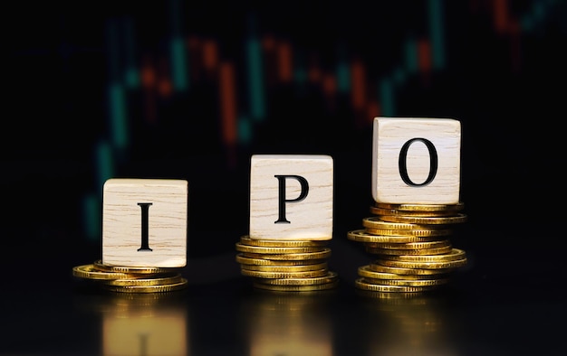 IPO のコンセプトです。積み上げられたコインの上に木製の立方体に書かれたテキスト IPO (新規株式公開)。