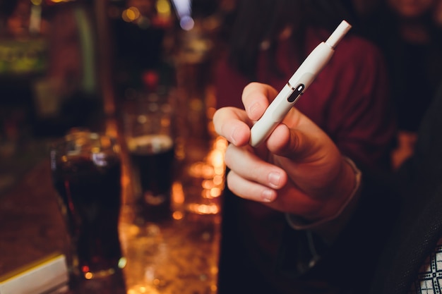 Технология табачных изделий, не перегреваемых IQOS. Человек, держащий e-сигарету в руке перед курением.