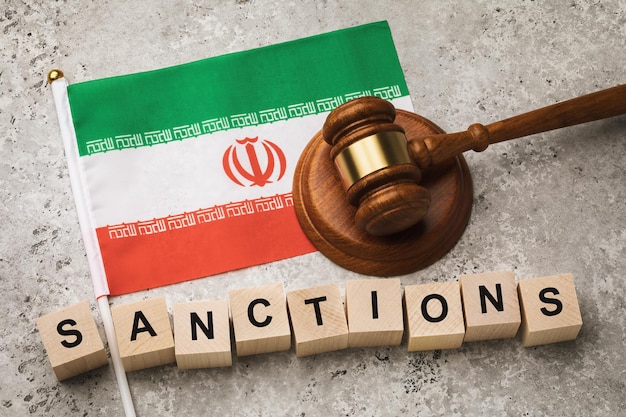 Iranian flag, judge's gavel and wooden cubes with text, concept on the topic of sanctions in Iran