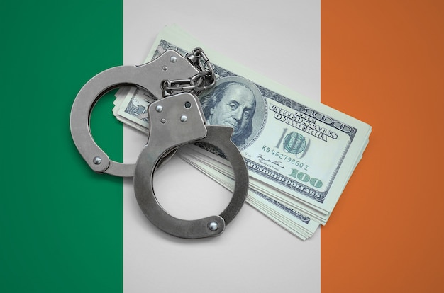 Ireland flag  with handcuffs and a bundle of dollars. Currency corruption in the country. Financial crimes