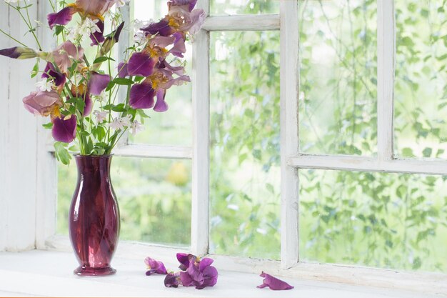 iris bloemen in glazen vaas op witte oude vensterbank