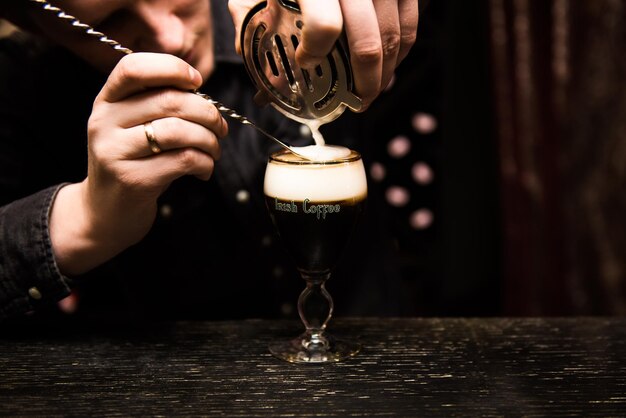 Irish Coffee-kopjes met room op een donkere achtergrond op het barverwarmende cocktailkookproces