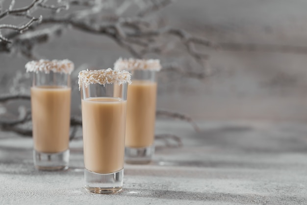 Irish cream Liquor or Coffee Liqueur with coconut flakes crown on top of short glass. Whinter holiday decorations