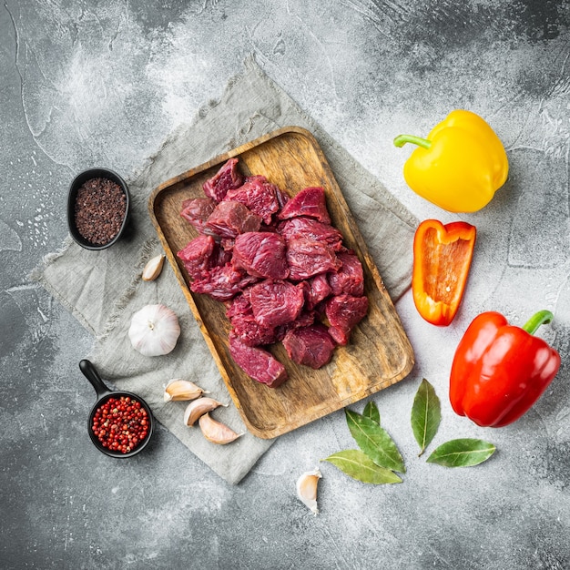 Irish raw Beef Stew Recipe ingredients set with sweet bell pepper, on gray stone background, top view flat lay, square format