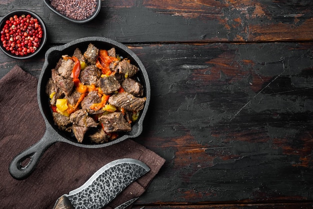 Irish stew made with beef potatoes carrots and herbs in cast iron frying pan on old dark wooden table top view flat lay with copy space for text