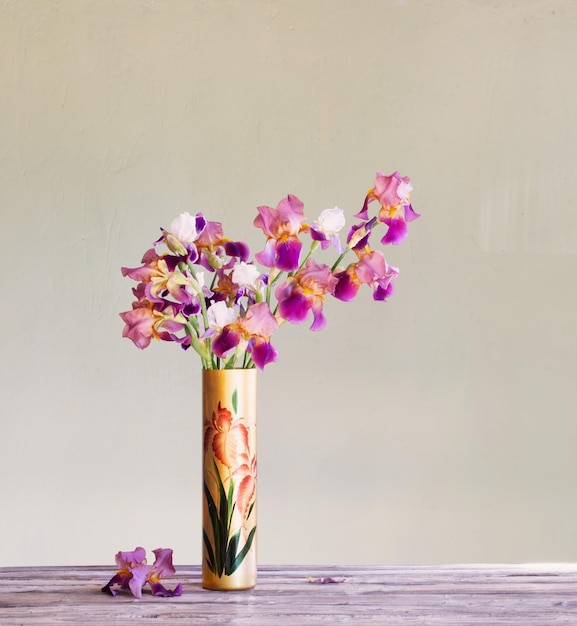 Irissen in mooie glazen vaas tegen groene muur