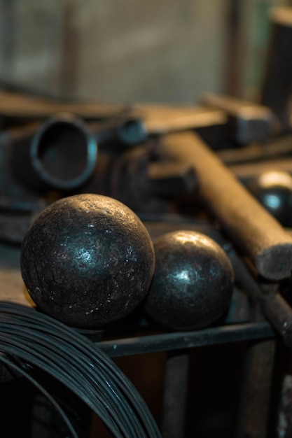 Iron balls on a work table in a blacksmith's workshop among tools close-up, vertical