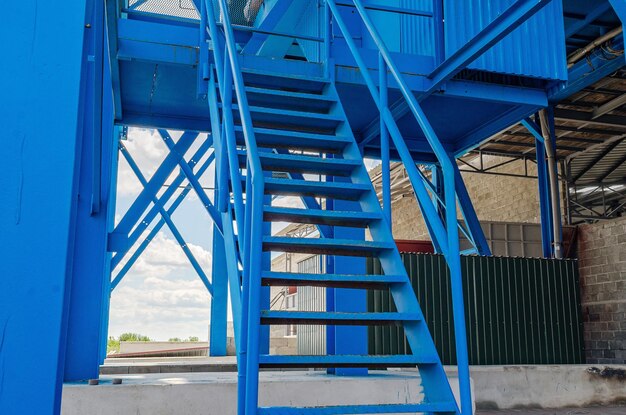 Iron blue stairs leading to production building modern solid stairs on background of plant