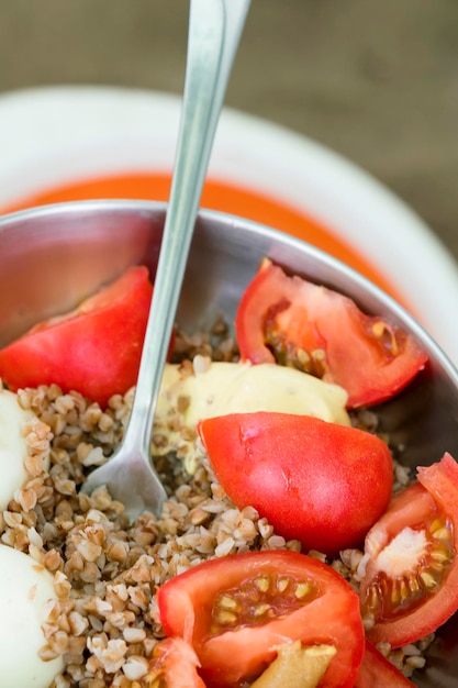 Iron bowl with buckwheat tomatoes boiled egg and fork