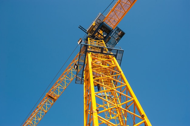 iron cabin of a yellow crane against a blue sky