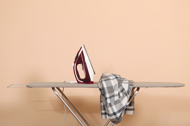 Iron and a clothes on an ironing board on a colored background