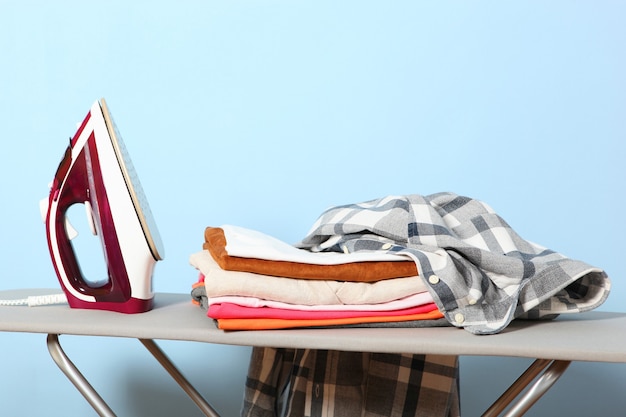 Iron and a clothes on an ironing board on a colored background