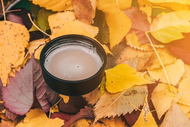 Iron cup with coffee on autumn foliage Thermosis in cold weather