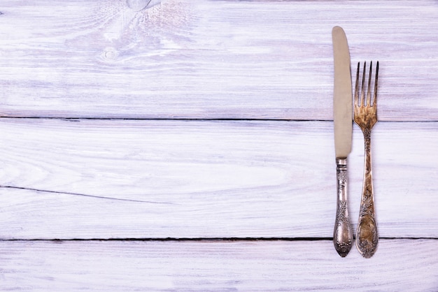 Iron fork and knife on a white wooden surface 