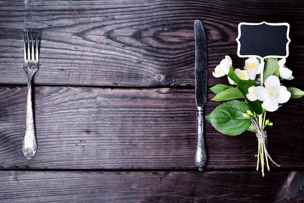 Forchetta e coltello in ferro con un bouquet di gelsomino