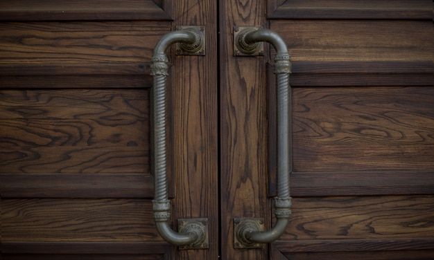 Iron handles on a wooden brown door on the street for design