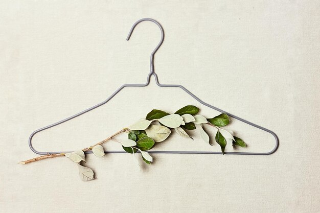 Photo iron hanger with trees sprig with leaves on linen background for eco-friendly sustainable design