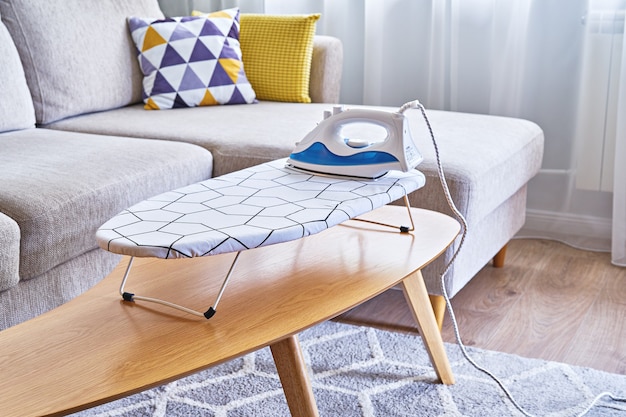 Iron for ironing on small tabletop ironing board in cozy and living room, small apartments