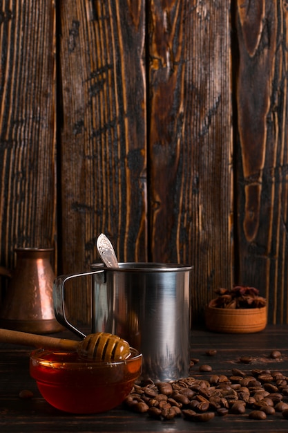 Iron mug with black coffee, honey and coffee beans on a wooden table. copyspace.