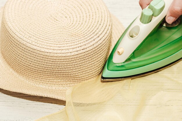 The iron smoothes the wrinkled brim of a straw hat