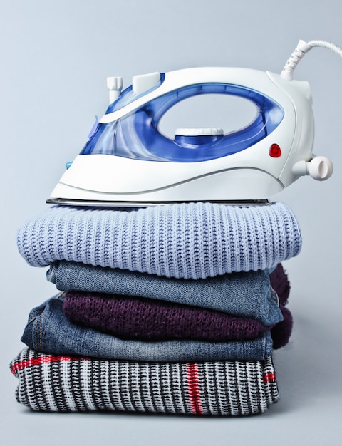 Iron on stack of clothes on gray table