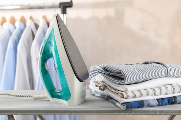 Photo iron and stack of t-shirts on ironing board,