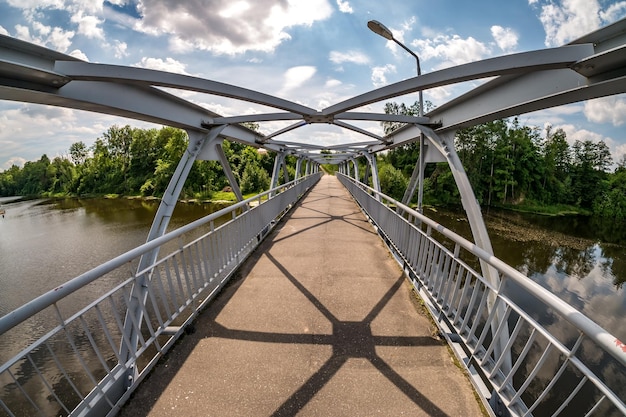 Iron steel frame construction of pedestrian bridge across the river wide angle view