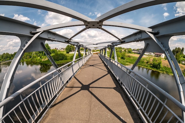 Iron steel frame construction of pedestrian bridge across the river wide angle view