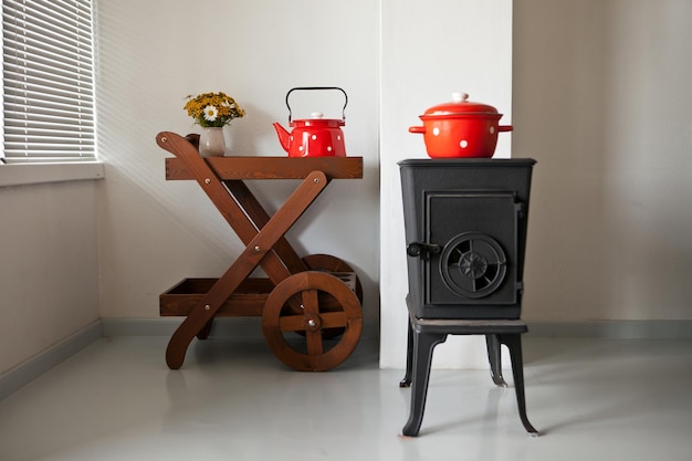 Iron stove at home interior in country house furnace is heated near window red tableware on table