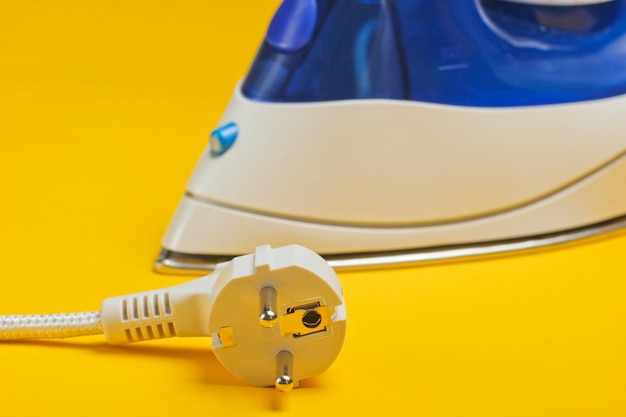 Iron with electric plug isolated on yellow