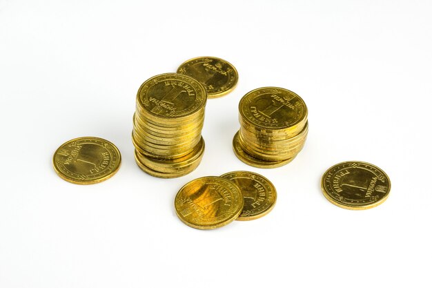 Железные желтые монеты номиналом 1 гривна лежат пачкой и стопками на белом фоне вырезок