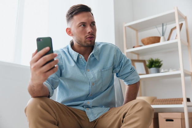 Irritated angry evil selfconfident handsome man trying to be\
calm tells with someone using video call at phone looks aside\
attractive guy hates operation mobile crash problems negative\
emotions