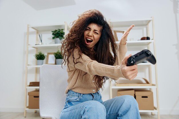 Irritated angry upset tanned curly latin lady lose game throw\
joystick gamepad aside close eyes sit on chair in home modern\
interior copy space mockup banner concept gamer people emotions\
concept