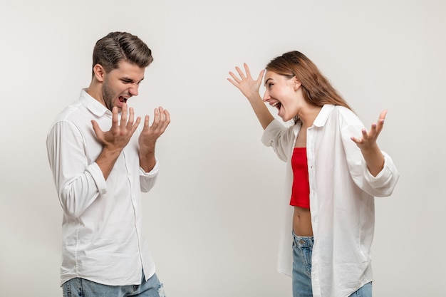 Irritated couple man and woman screaming at each other standing face to face over white background