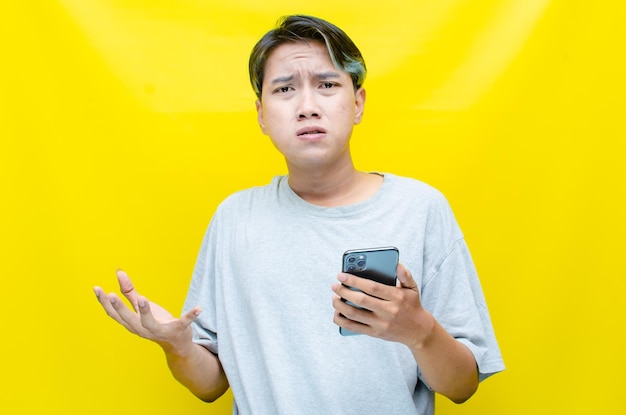 Irritated depressed and messed asian young man shouting to phone madly and angrily