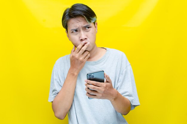 Irritated depressed and messed asian young man shouting to phone madly and angrily