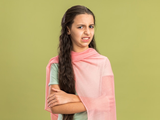 Irritated teenage girl wearing shawl standing with closed posture looking at front isolated on olive green wall with copy space