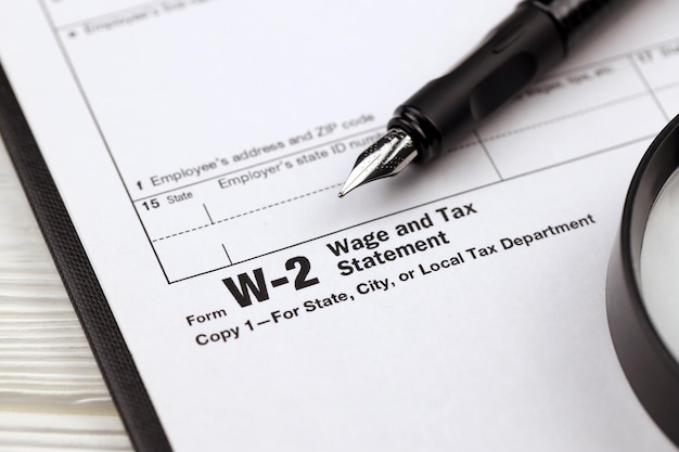 Photo irs form w wage and tax statement blank on a tablet lies on office table with pen and magnifying