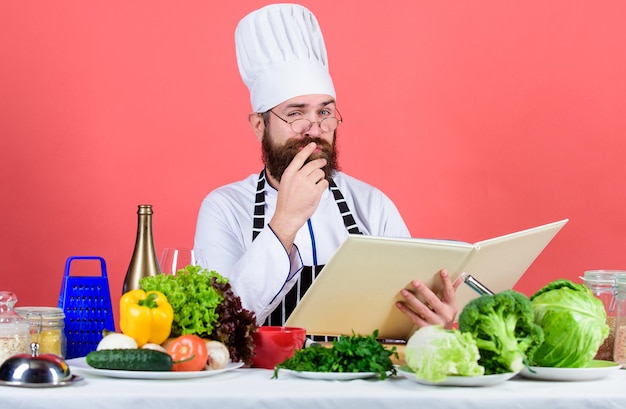 管理下にあります。ダイエットと有機食品、ビタミン。ひげを生やした男がキッチンで料理をします。健康的な料理。帽子をかぶったシェフの男。秘密の味のレシピ。ベジタリアン。あごひげを生やした成熟したシェフ。