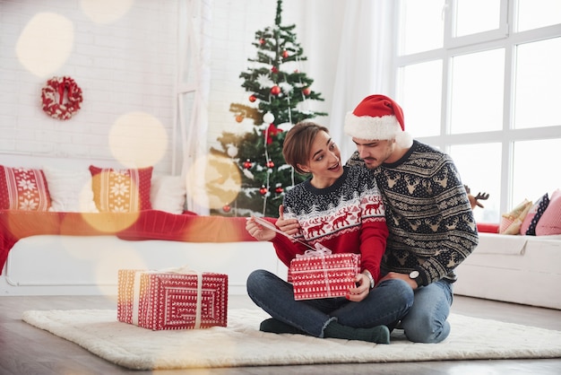 Is dat waar ik aan denk. man verrast zijn vrouw voor kerstmis in de mooie kamer met kerstversiering.